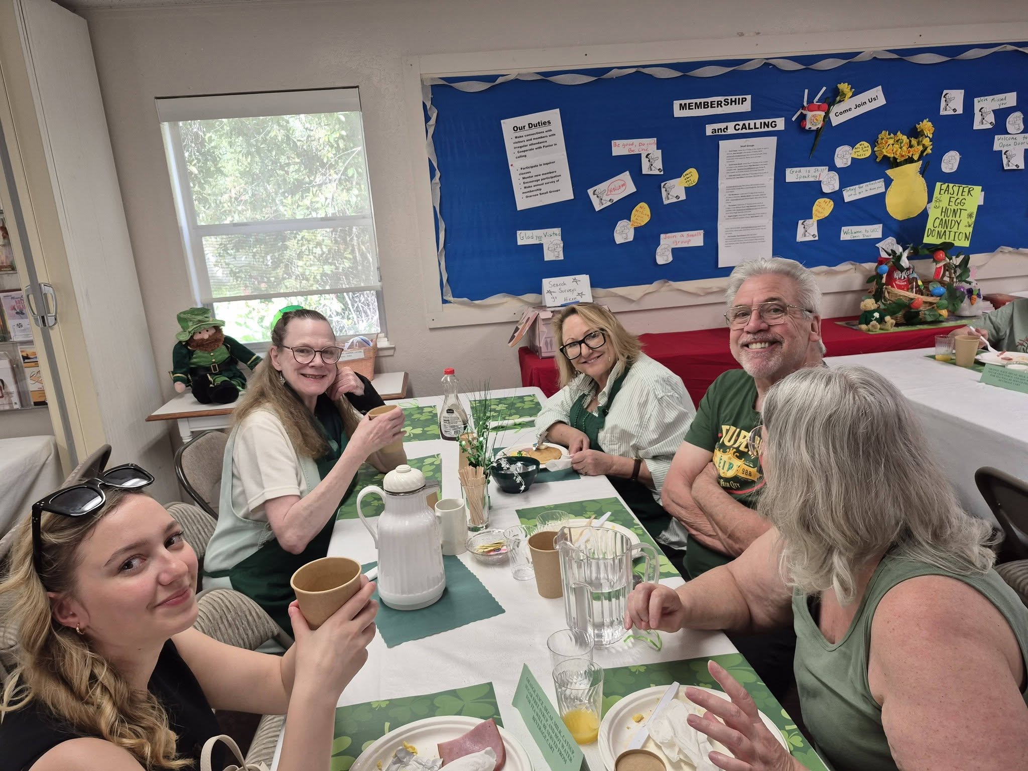 Church members smiling around a table together at a pancake breakfast