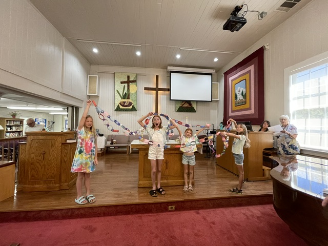 Children and adults dancing with streamers in the sanctuary during Vacation Bible School